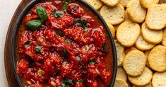 an oval dish filled with tomato sauce next to crackers