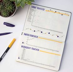 two notebooks sitting on top of a white table next to a potted plant