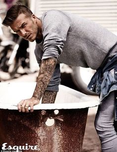 a man with tattoos leaning over an old tub