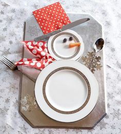 there is a snowman made out of plates and silverware on this table cloth