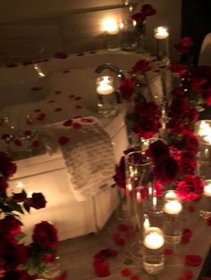 candles are lit in the bathtub surrounded by red flowers and roses on the floor