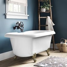 a white bath tub sitting next to a wooden ladder in a blue bathroom with wood flooring