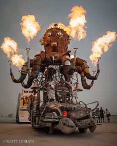 an art piece with fire coming out of it's head and arms, in the shape of a robot