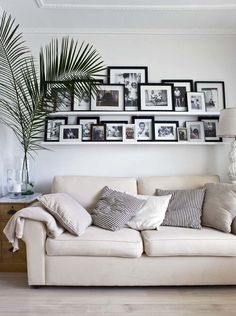 a white couch sitting in front of a wall filled with pictures and framed photos on it