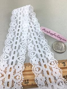 a ruler and some white lace next to a roll of measuring tape on a table