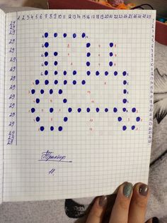 a person holding up a piece of paper with blue dots on it