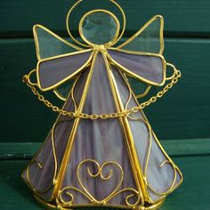 a stained glass angel ornament hanging on a green door with gold chains around it