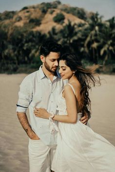 a man and woman standing next to each other on a beach