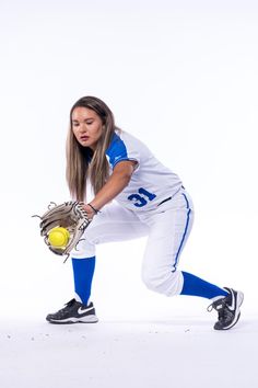 a woman in a baseball uniform holding a ball and glove