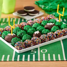 football themed desserts are arranged on a table with green napkins and black cookies