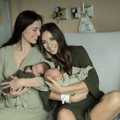 two women sitting on a couch holding a baby