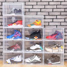 a stack of clear plastic boxes filled with different colored nike shoes in front of a brick wall