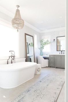 a large white bath tub sitting next to a sink in a bathroom under a window