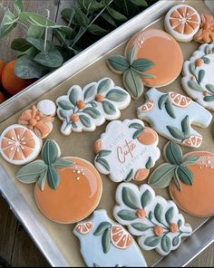 decorated cookies with oranges and leaves on a tray