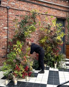 a person bending over to pick up some plants