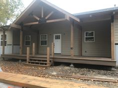 a small gray house sitting on top of a wooden floor next to a forest filled with trees