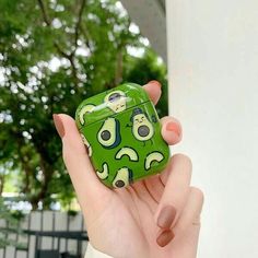 a person holding an avocado airpods case in their hand