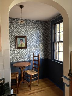 a dining room with a table and two chairs in front of a painting on the wall