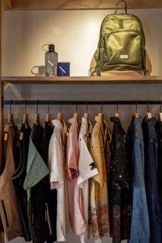 the closet is full of clothes and handbags on hangers, with a backpack in the background