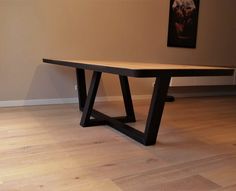 a wooden table sitting on top of a hard wood floor next to a white wall