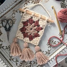 a crocheted square with tassels and yarn on it next to scissors