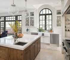 a large kitchen with white cabinets and black counter tops, along with an island in the middle