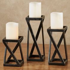 three candle holders with white candles in them