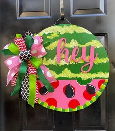 a door hanger with the word hey painted on it and a bow attached to it