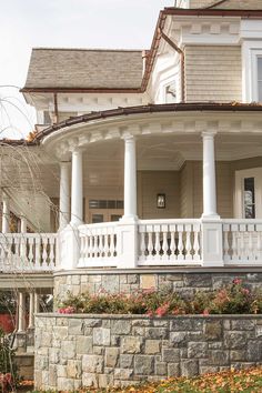 the front porch of a house with white columns and flowers on the planter boxes