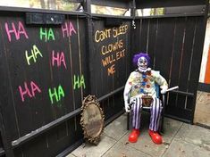 a clown sitting in a chair next to a wall with writing on it