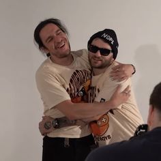 two men hugging each other in front of a camera