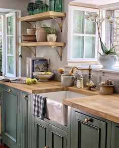 a kitchen filled with lots of green cabinets and wooden counter tops next to a window