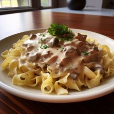 a white plate topped with pasta covered in gravy and meat on top of it