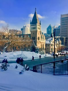 people are walking through the snow in front of a large building with a steeple