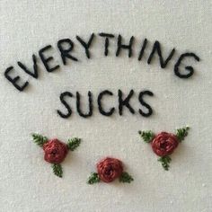 the words everything sucks written in black and red thread with roses on it's side