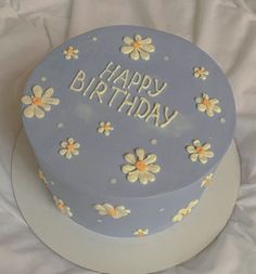 a birthday cake with daisies and the words happy birthday written on it in frosting