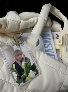 a white purse with a keychain that has a photo of a boy on it