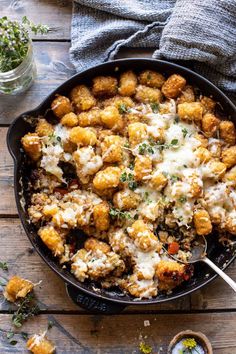 a skillet filled with tater tots covered in cheese and parmesan