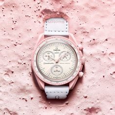 The Swatch X Omega Bioceramic Moonswatch Mission To Venus (So33p100) Features Pastel Pink Hues Contrasted With Beige And A White Velcro Strap, Reminiscent Of The Pastel Hues Prominent On The Surface Of Our Neighbor Venus. The Swatch X Omega Mission To Venus (So33p100) Features Pink Hours, Minutes, Second, And Counter Hands, And Swatch Calls The Diamond-Like Details On The Edges A "Touch Of Feminine Elegance." The Watch, Like The Others In The Collection, Also Features Quartz Movement And Is 3 Ba Moon Swatch, Mission To Mercury, Swatch Store, Omega X Swatch, Logo Elements, Omega Speedmaster Moonwatch, Moon Watch, Black Backdrop, Omega X