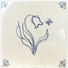 a blue and white tile with a butterfly on it's back side in the shape of a flower