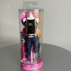 a toy doll in a plastic case on top of a table with white walls behind it