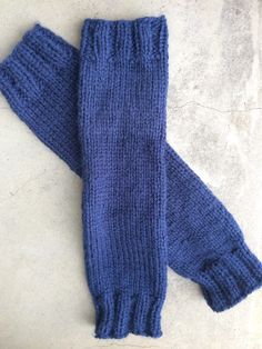 a pair of blue knitted gloves laying on top of a white floor next to each other