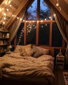 a bed in a room with lights strung from the ceiling and pillows on top of it