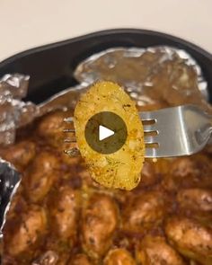 a fork with some food on it in a pan next to another dish that includes meat and potatoes