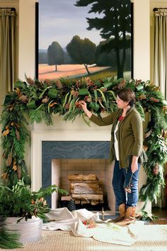 a woman standing in front of a fire place holding a christmas wreath over her head