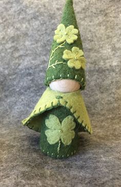 a green felt christmas tree with four leaf clovers on it's top, sitting on a gray surface