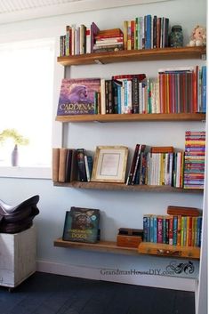 two wooden shelves filled with books next to a window