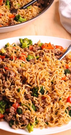 two plates filled with noodles, meat and vegetables