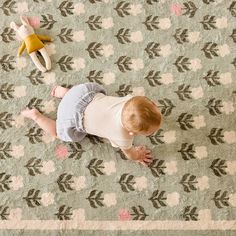 a toddler playing on a rug with two stuffed animals next to it and another toy