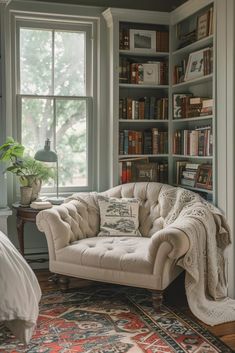 a couch sitting in front of a window next to a book shelf filled with books